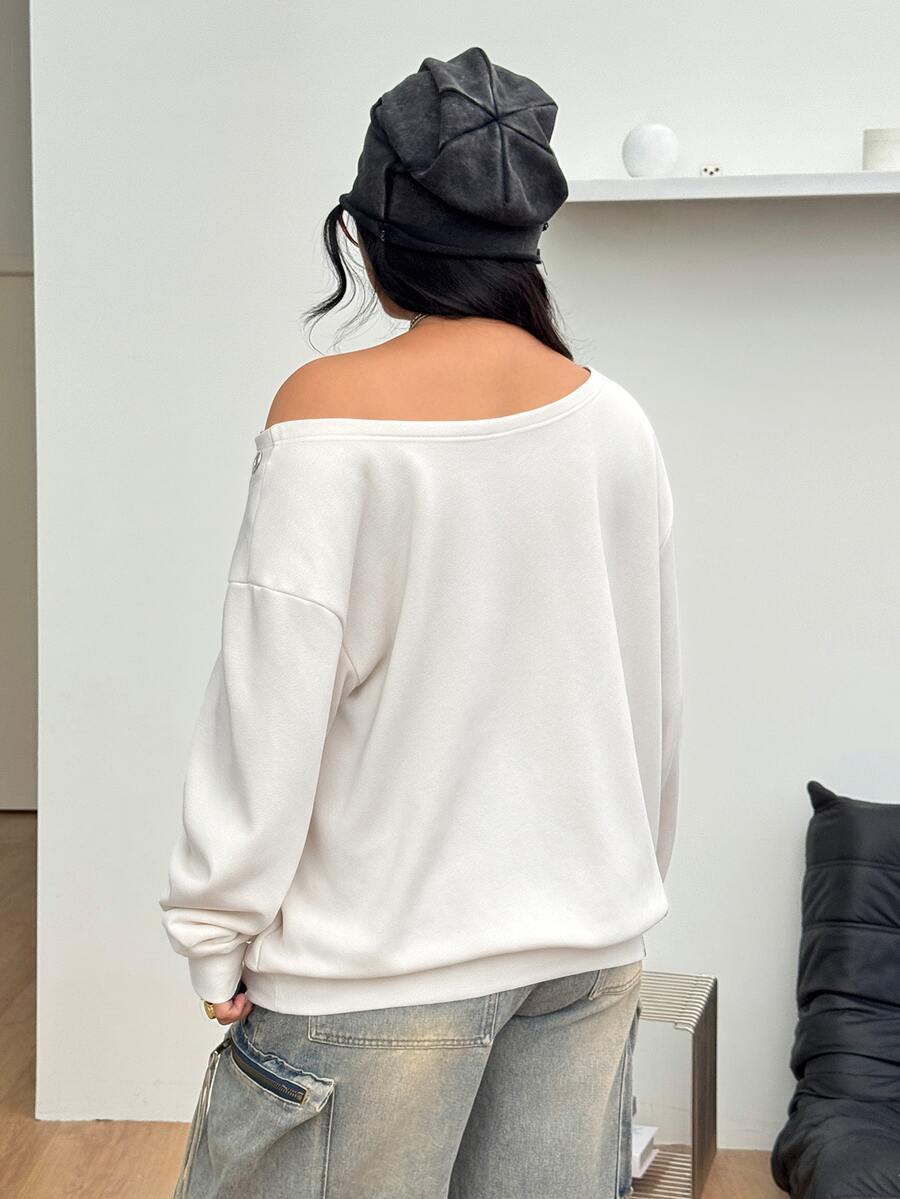 Women's oversized dark grey long sleeve sweatshirt featuring an asymmetrical boat neckline with grommet eyelet details and drop shoulders.