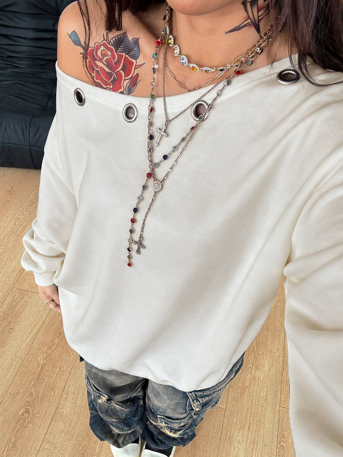Women's oversized dark grey long sleeve sweatshirt featuring an asymmetrical boat neckline with grommet eyelet details and drop shoulders.