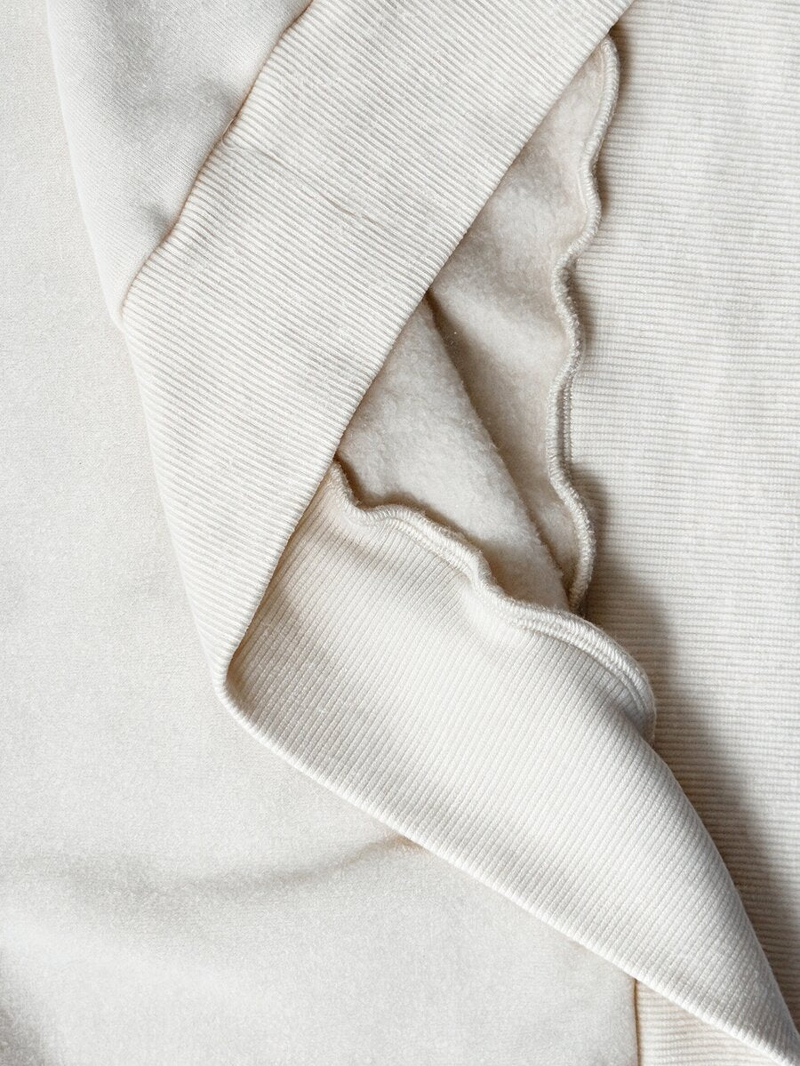 Women's oversized dark grey long sleeve sweatshirt featuring an asymmetrical boat neckline with grommet eyelet details and drop shoulders.