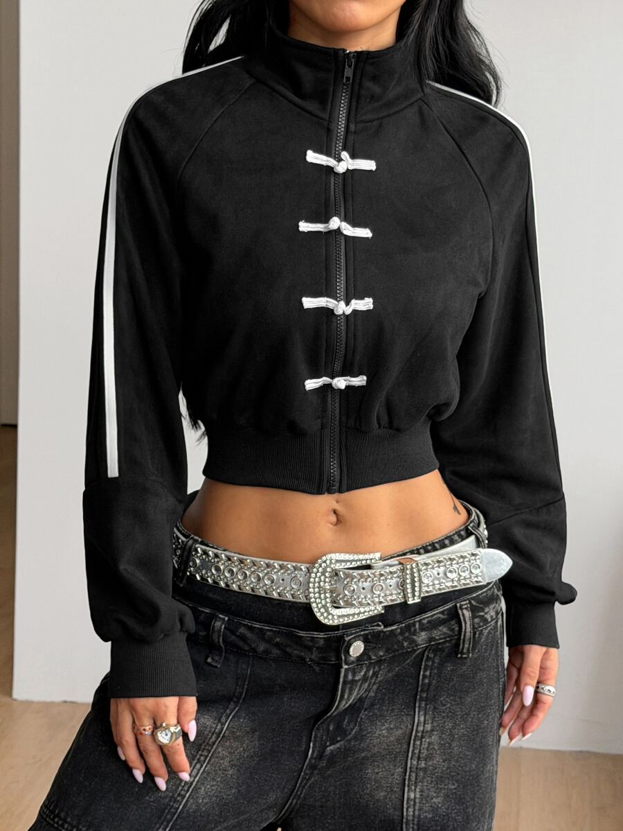 Women's black cropped track jacket with white colorblock tape details, stand collar, and front zip closure.