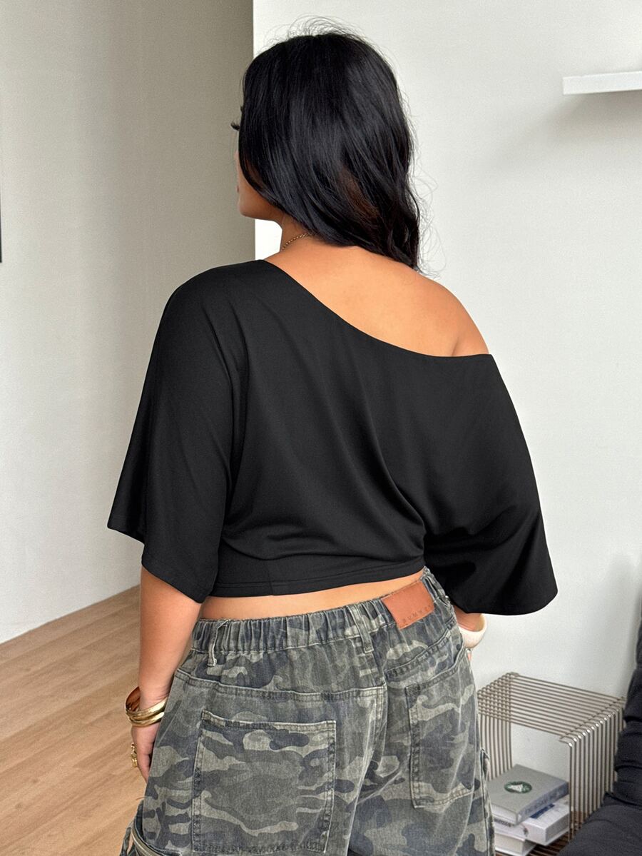 Black plus size cropped knit t-shirt featuring an asymmetrical scoop neckline, three-quarter batwing sleeves, and a loose casual fit.