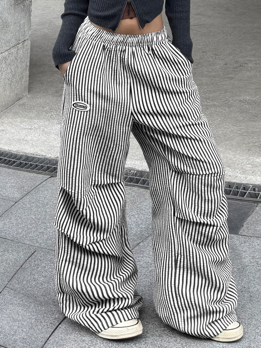 Women's black and white striped wide leg pants featuring an elastic drawstring waistband, side pockets, and a loose straight leg fit.