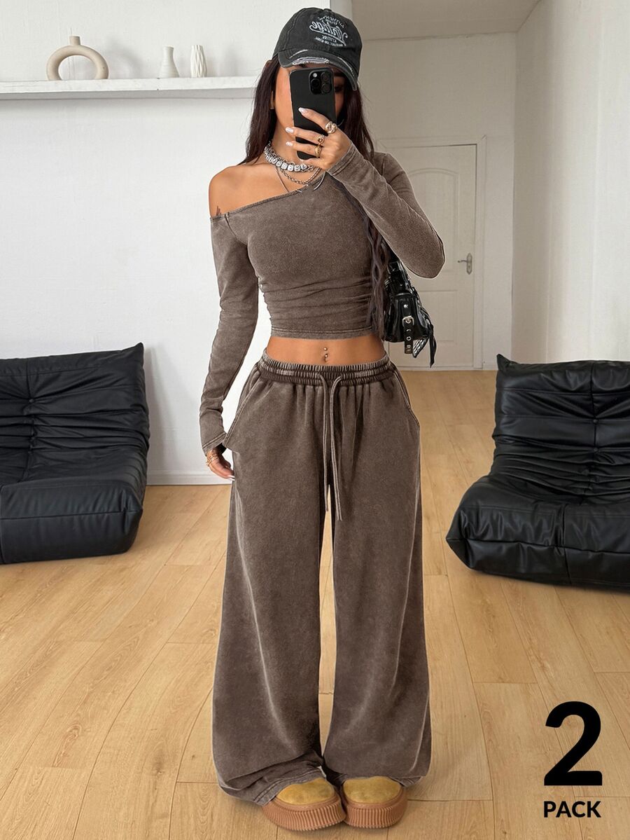 Women's two-piece knit lounge set featuring a black long sleeve asymmetrical crop top and matching high-waisted wide leg sweatpants.