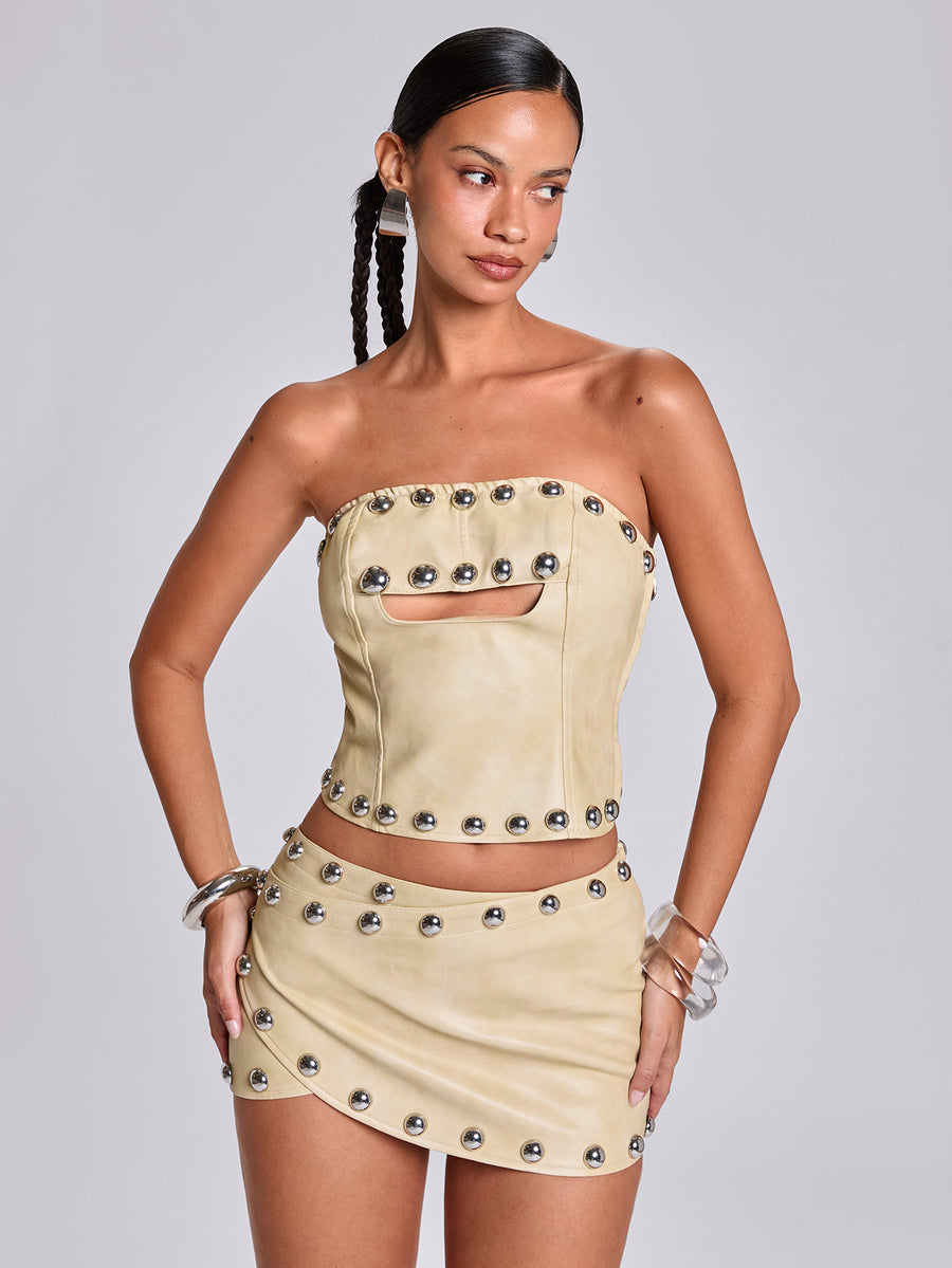 Women's bodycon mini skirt featuring an ultra low layered waistline with studded rivet details in a solid color finish.