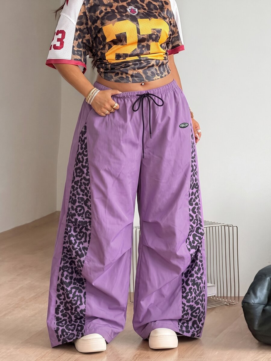 Women's high waist wide leg pants in black featuring leopard print patchwork details and an elastic drawstring waistband.