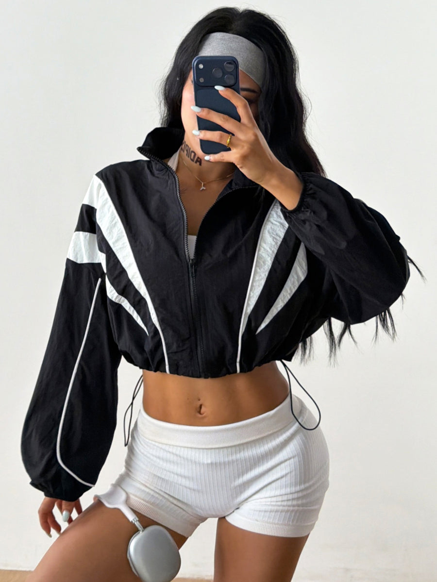 Black cropped lightweight sports jacket for women featuring colorblock stripes, a funnel neck, long sleeves, and a zipper closure.
