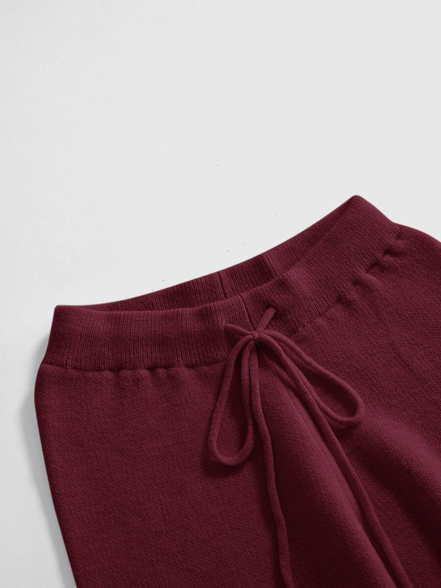 Women's two-piece rib-knit sweater set featuring a long-sleeve cold-shoulder crop top with strap details and matching wide-leg pants.