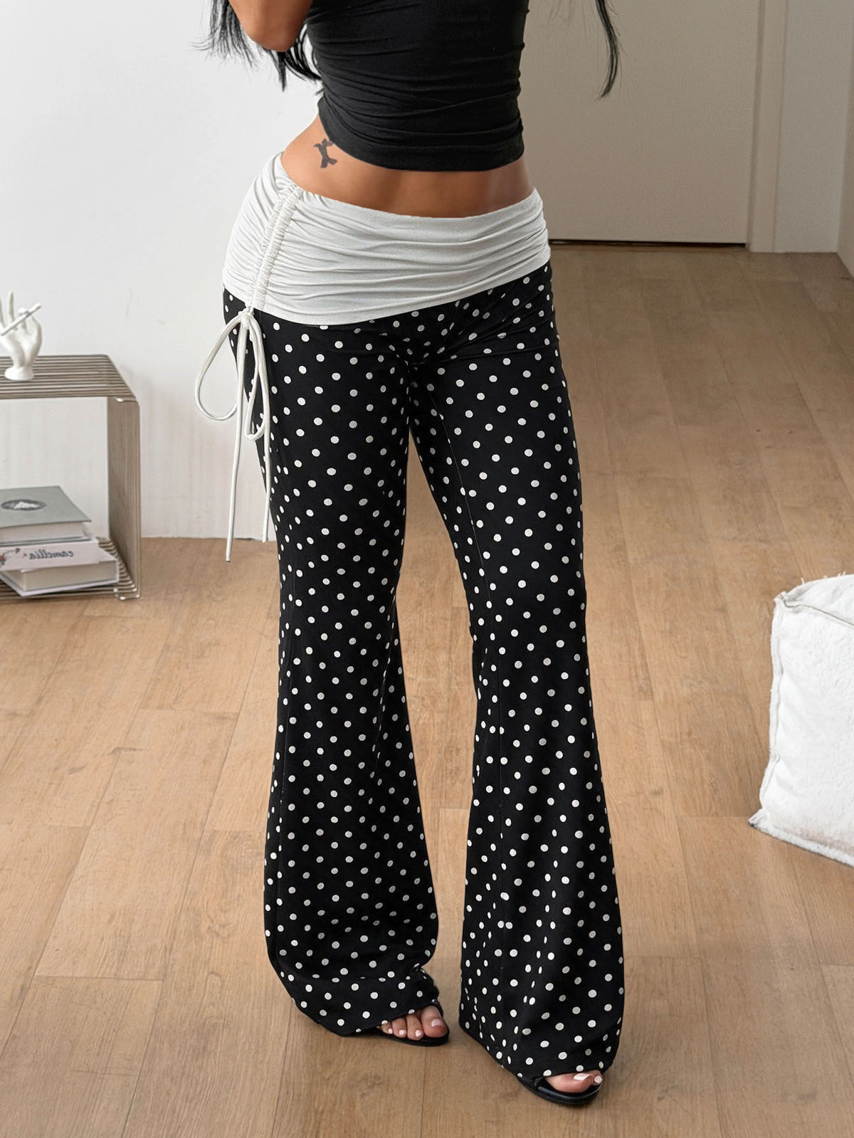Women's black and white polka dot flare leg pants with side drawstring and ruched details