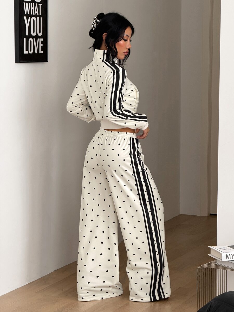 Women's two-piece black and white polka dot set featuring a short zip-up mock neck sweatshirt and matching wide-leg sweatpants.