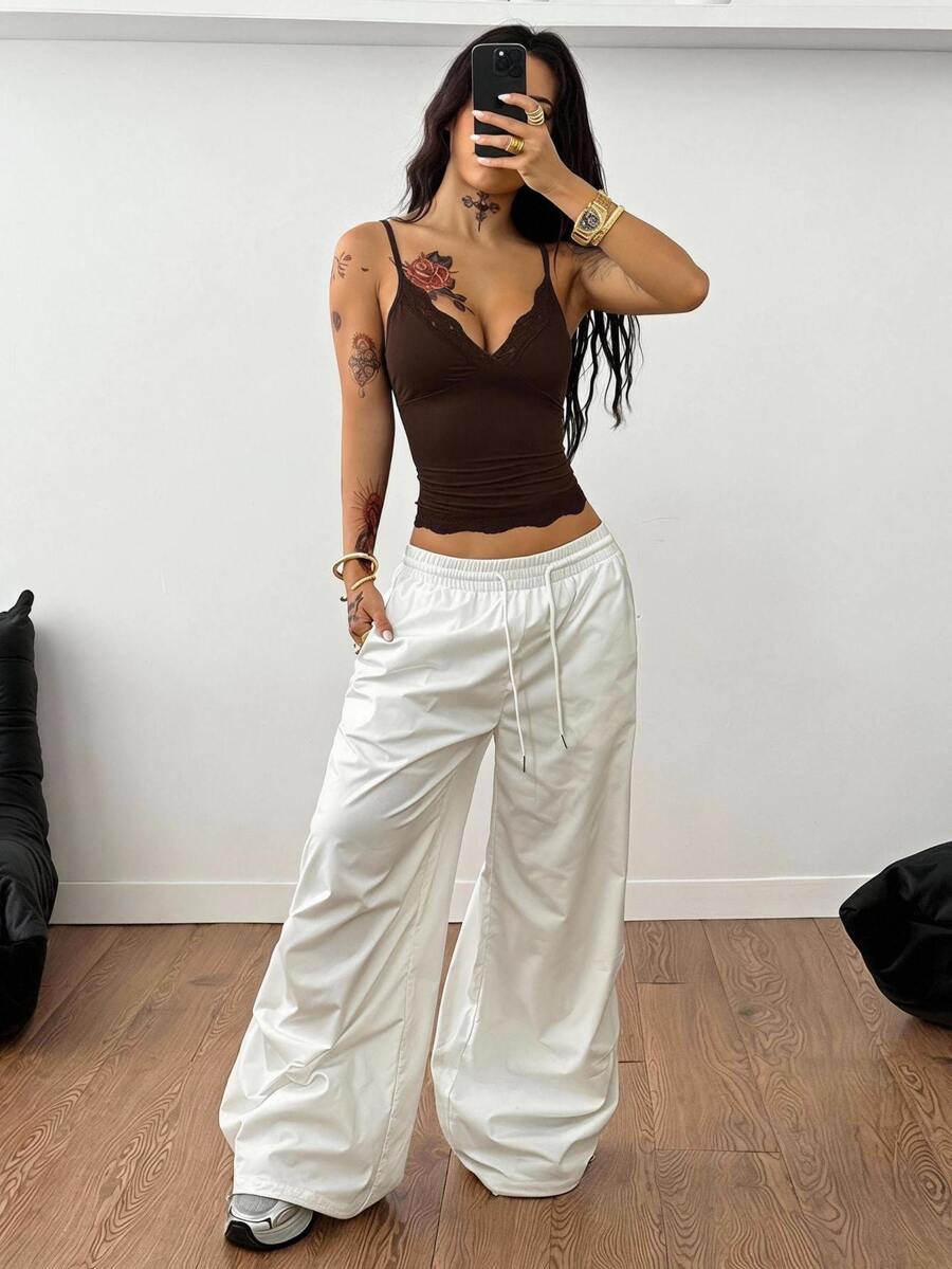 Slim fit cropped camisole top for women featuring contrast lace trim, ruched cup detailing, and delicate spaghetti straps.