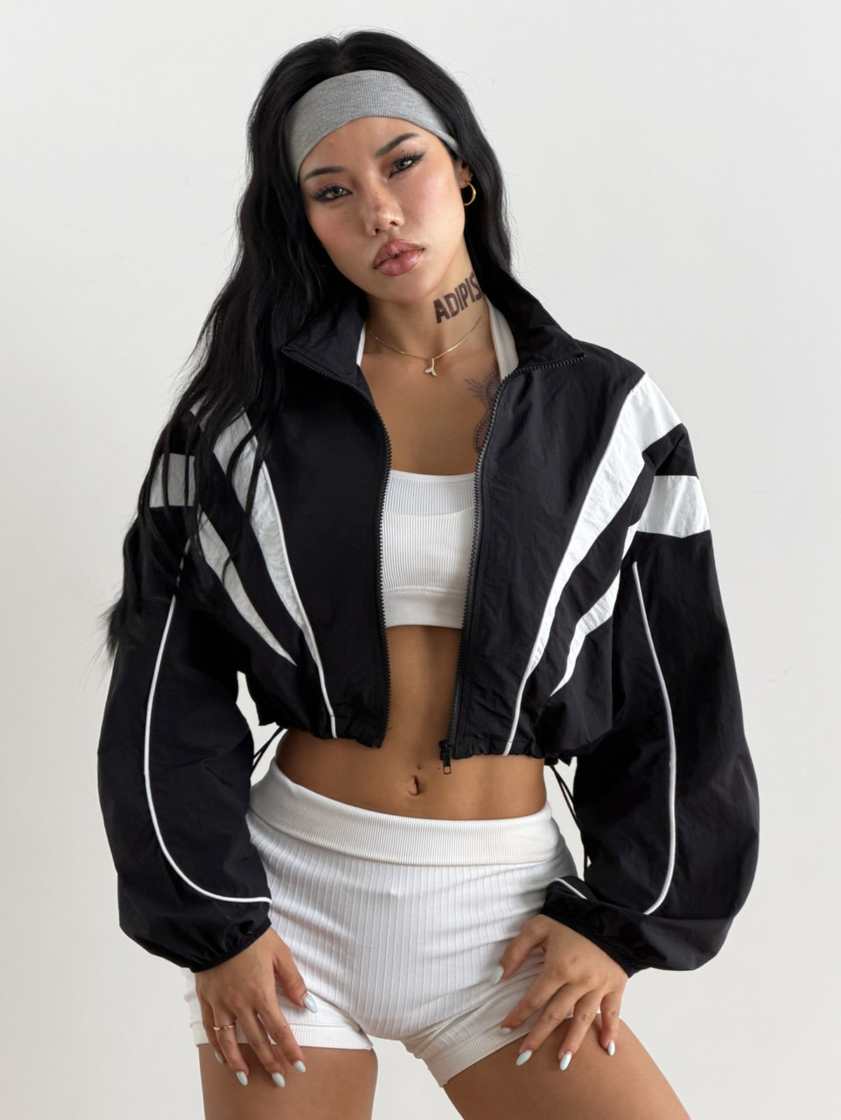Black cropped lightweight sports jacket for women featuring colorblock stripes, a funnel neck, long sleeves, and a zipper closure.