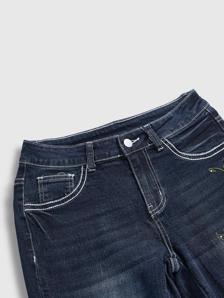 Women's blue ultra low waist flare jeans with butterfly vine embroidery and rhinestone detailing on stretch denim.