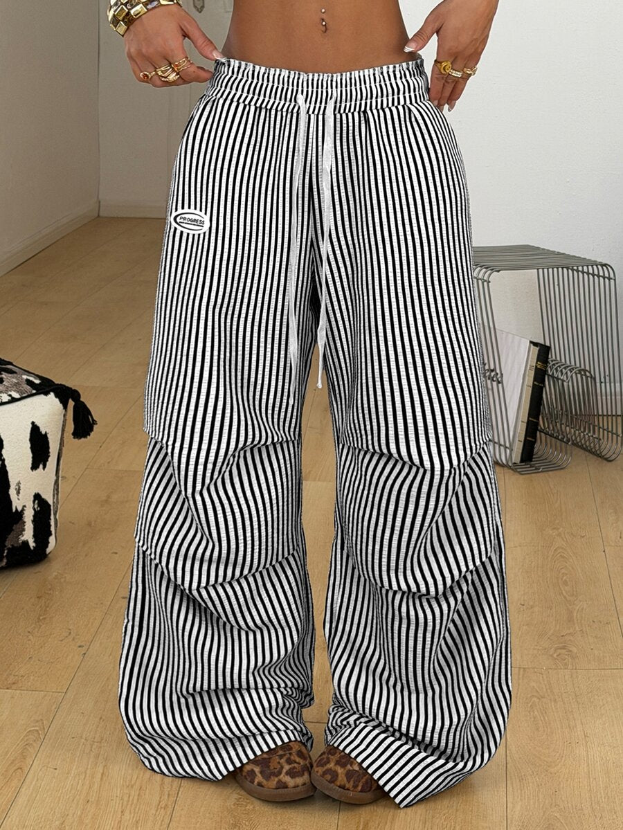 Women's black and white striped wide leg pants featuring an elastic drawstring waistband, side pockets, and a loose straight leg fit.
