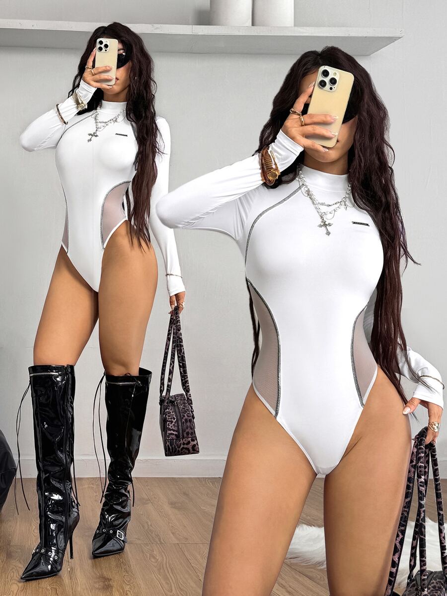 White long sleeve knit bodysuit featuring a front zip-up stand collar and contrast sheer mesh panels in a slim fit silhouette.