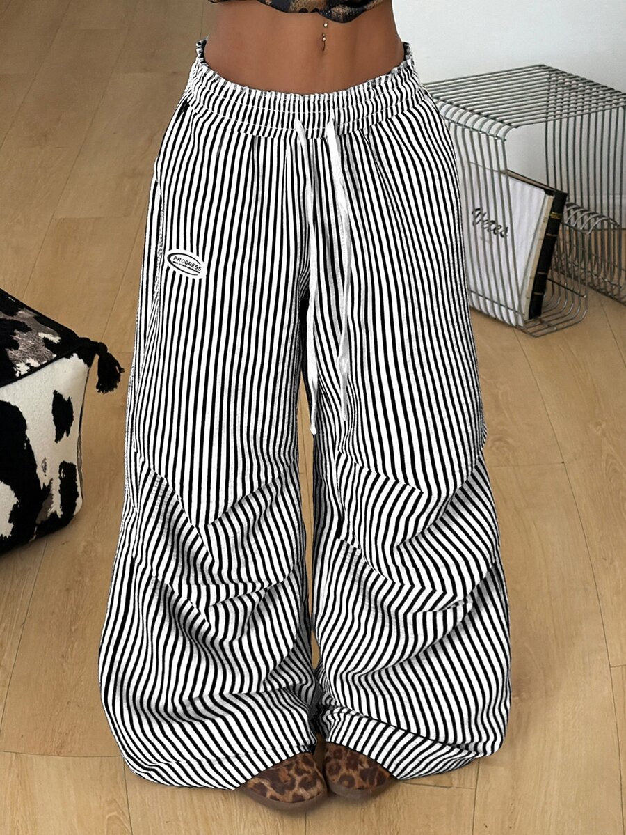 Women's black and white striped wide leg pants featuring an elastic drawstring waistband, side pockets, and a loose straight leg fit.