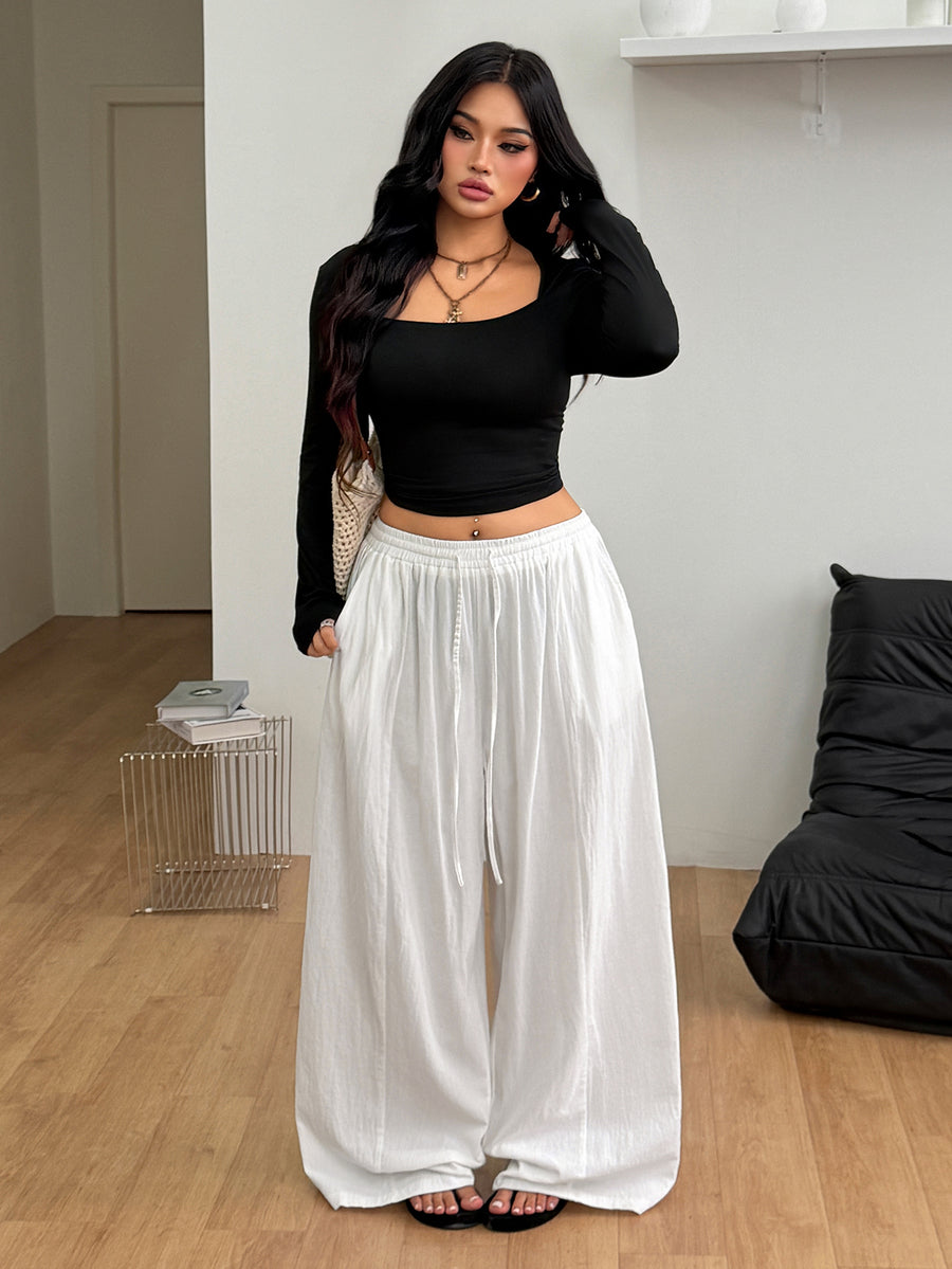 Women's loose straight leg cotton pants featuring a high waist with an adjustable drawstring knot and functional side pockets.