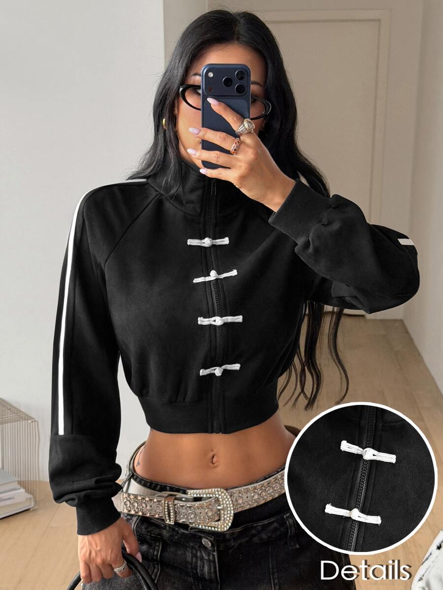 Women's black cropped track jacket with white colorblock tape details, stand collar, and front zip closure.