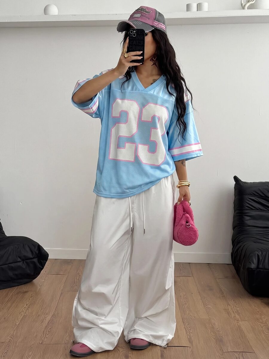 Oversized short-sleeve football jersey top featuring a V-neckline, contrast binding, and graphic number print.