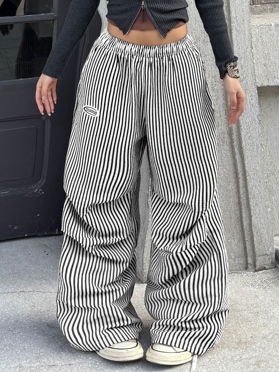 Women's black and white striped wide leg pants featuring an elastic drawstring waistband, side pockets, and a loose straight leg fit.