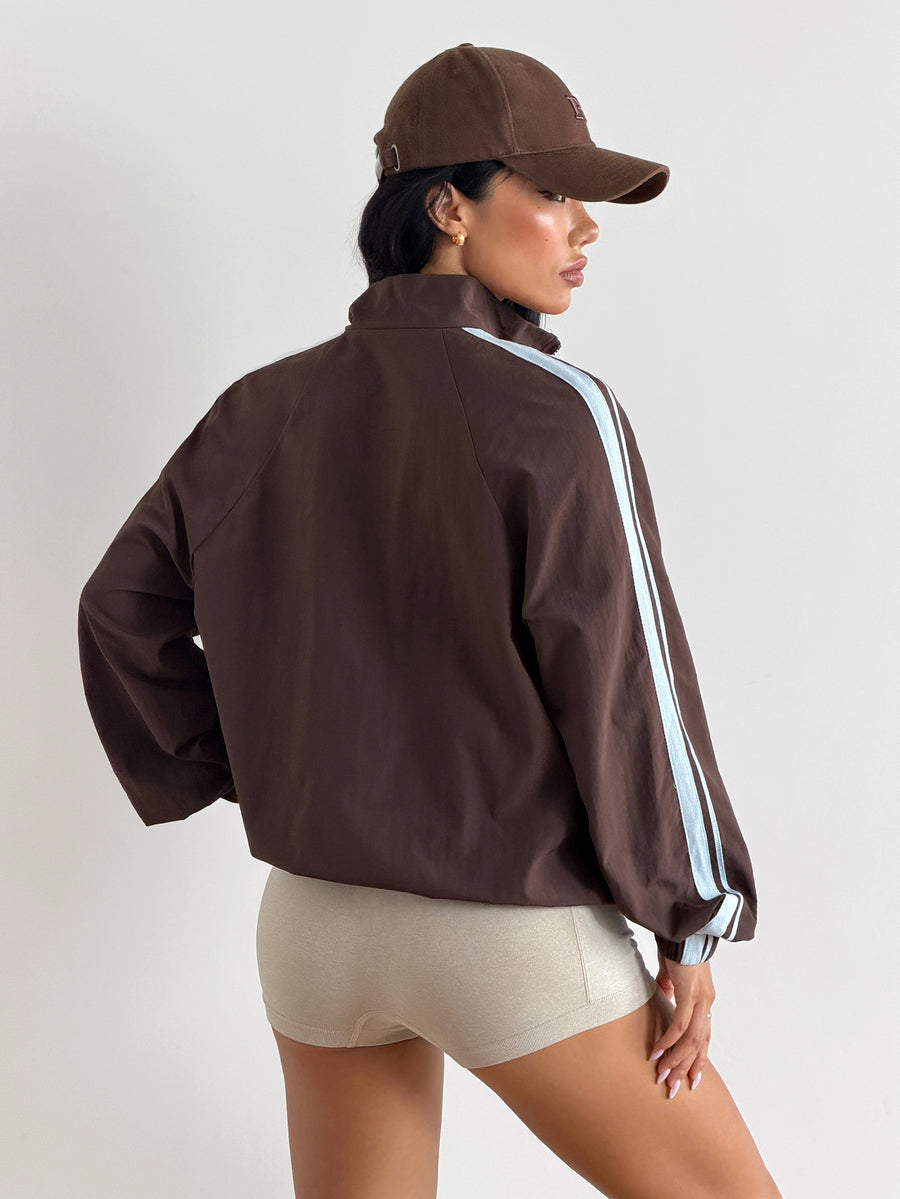 Front view of a women's oversized coffee brown sports jacket featuring a high neckline, front zipper closure, and long sleeves.