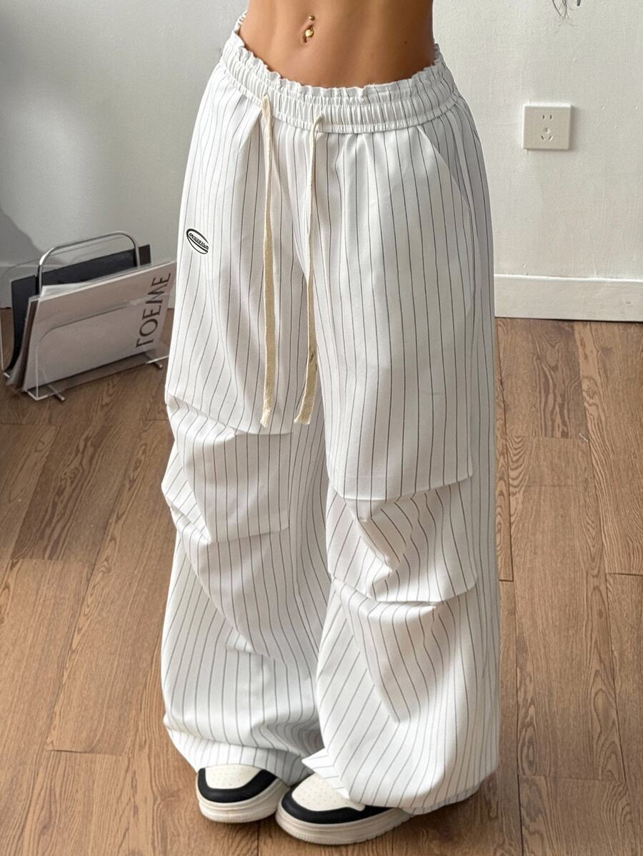 Women's black and white striped wide leg pants featuring an elastic drawstring waistband, side pockets, and a loose straight leg fit.