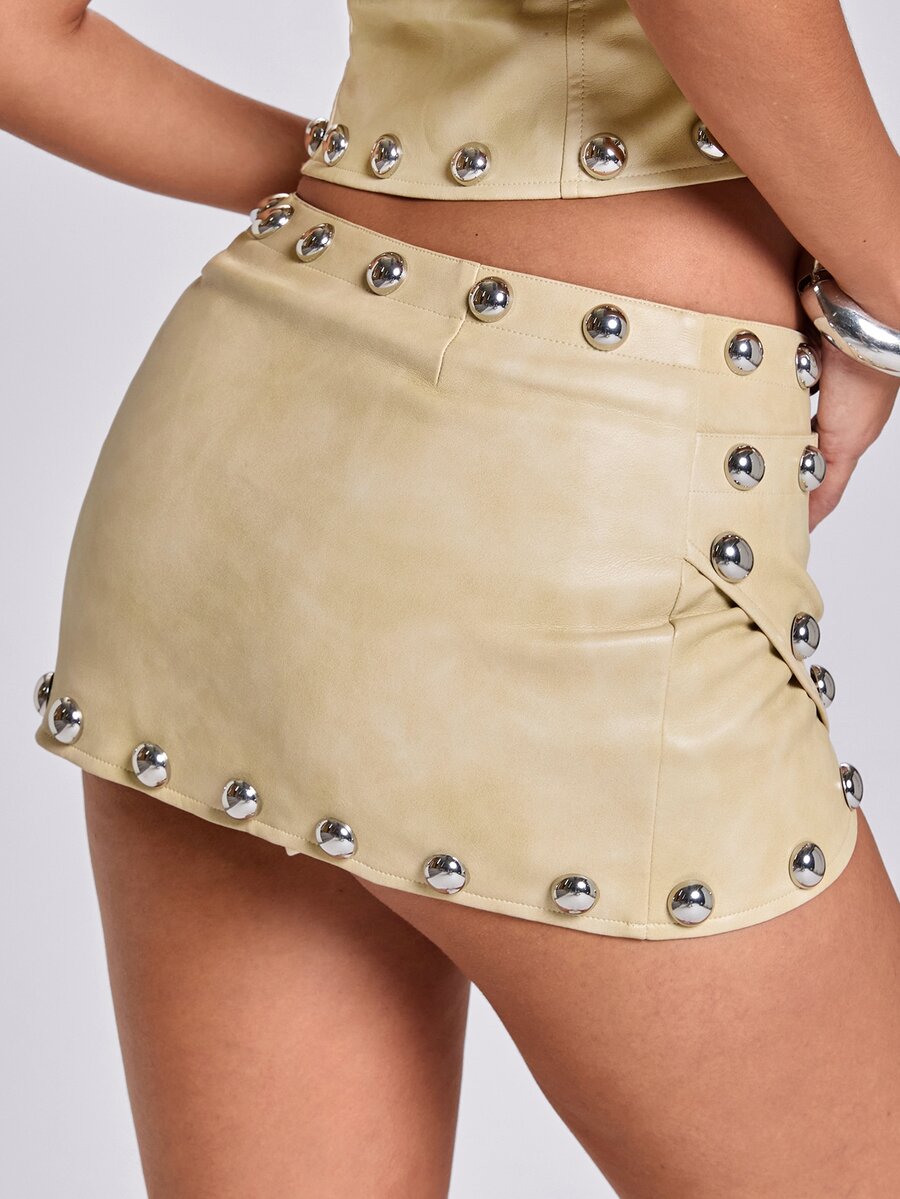 Women's bodycon mini skirt featuring an ultra low layered waistline with studded rivet details in a solid color finish.