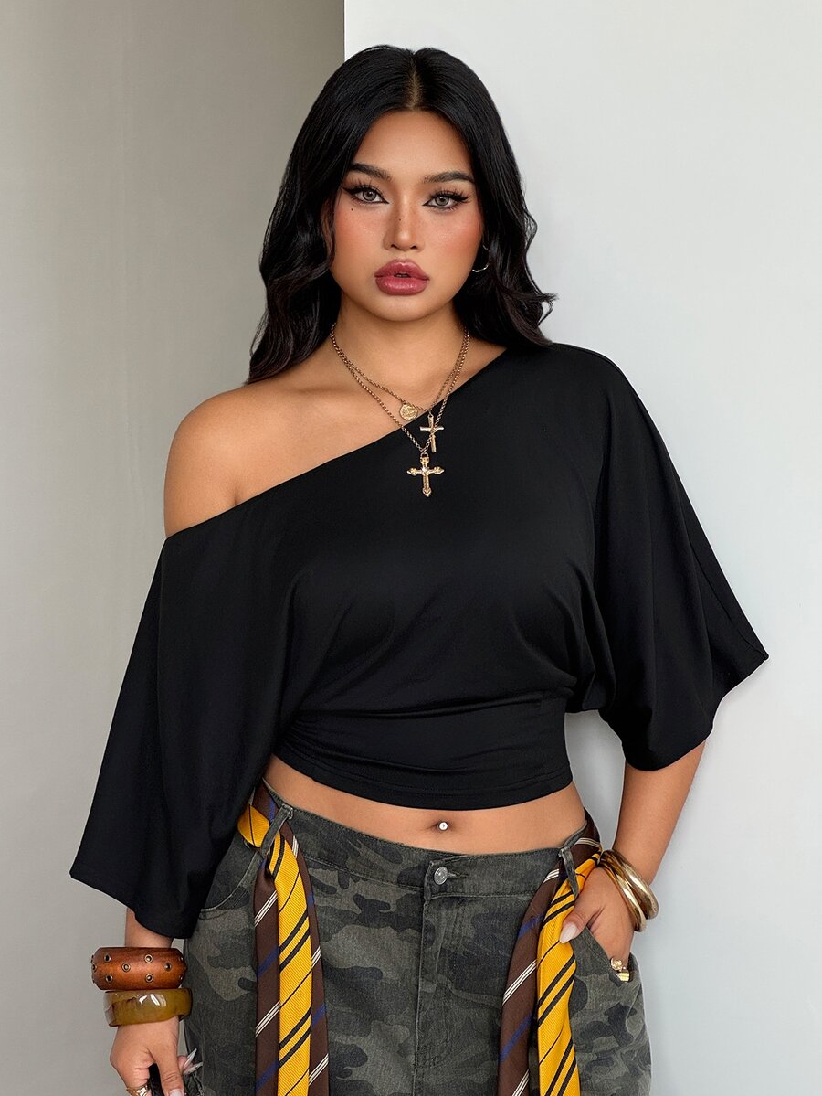 Black plus size cropped knit t-shirt featuring an asymmetrical scoop neckline, three-quarter batwing sleeves, and a loose casual fit.