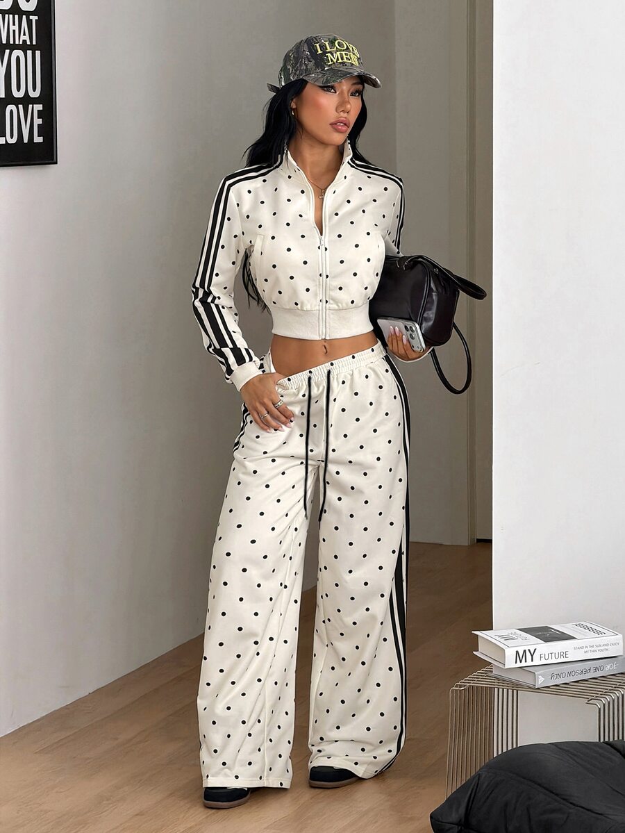 Women's two-piece black and white polka dot set featuring a short zip-up mock neck sweatshirt and matching wide-leg sweatpants.