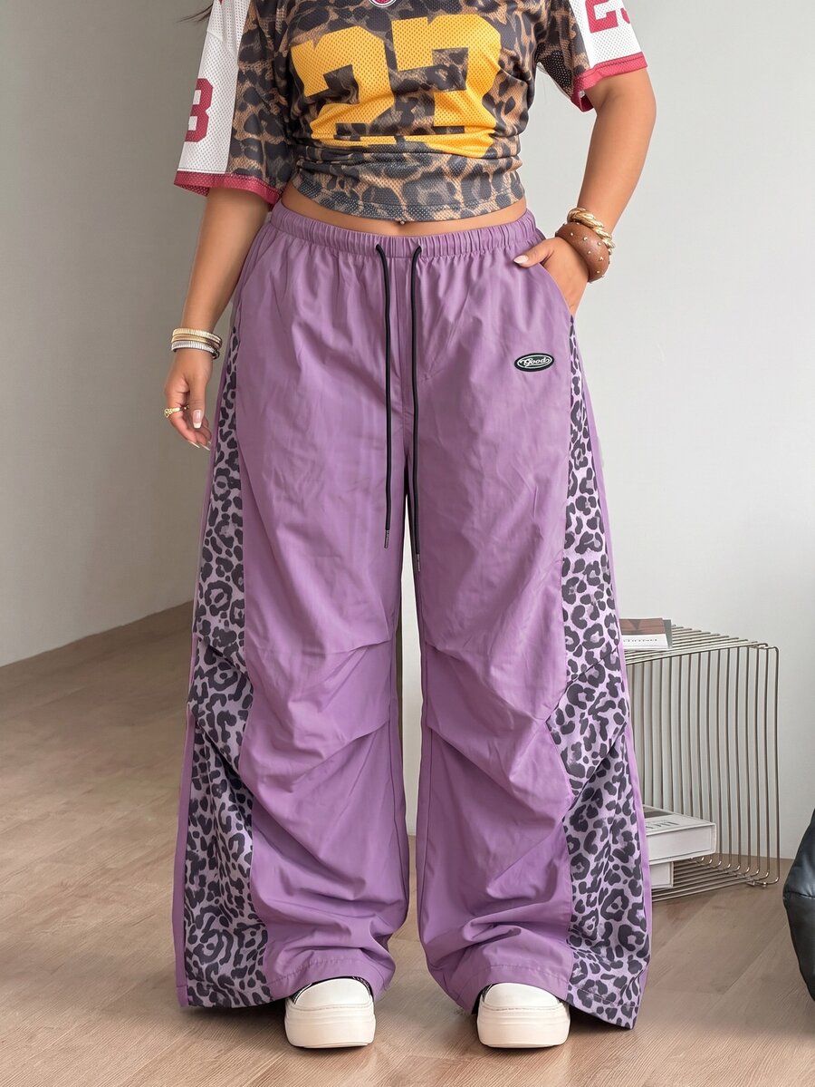 Women's high waist wide leg pants in black featuring leopard print patchwork details and an elastic drawstring waistband.