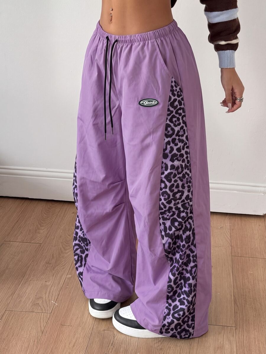 Women's high waist wide leg pants in black featuring leopard print patchwork details and an elastic drawstring waistband.