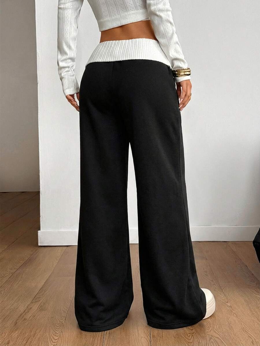 Women's wide leg flare sweatpants featuring a black and white colorblock contrast fold waistband and side stripe details.