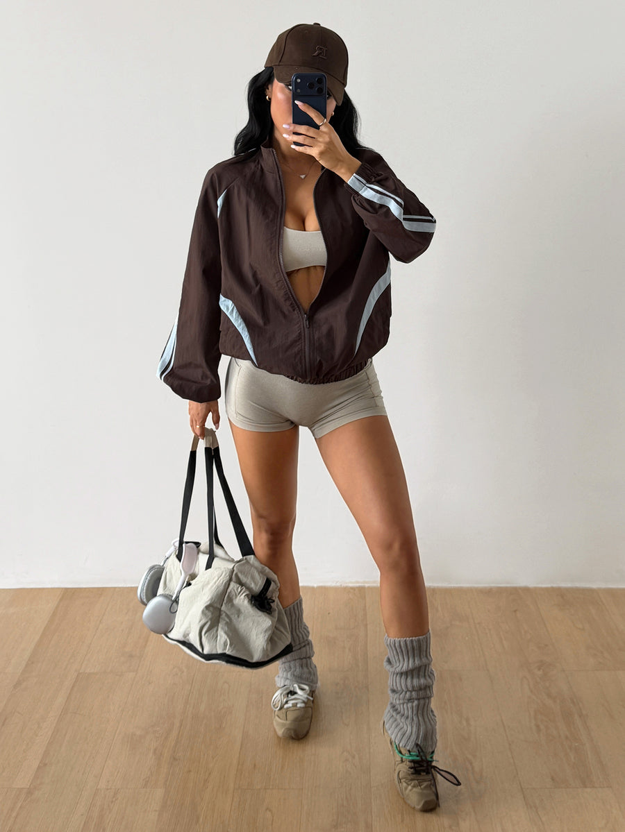 Front view of a women's oversized coffee brown sports jacket featuring a high neckline, front zipper closure, and long sleeves.