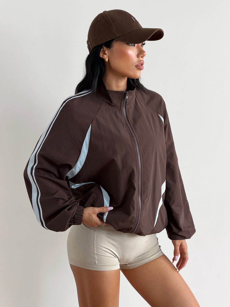 Front view of a women's oversized coffee brown sports jacket featuring a high neckline, front zipper closure, and long sleeves.