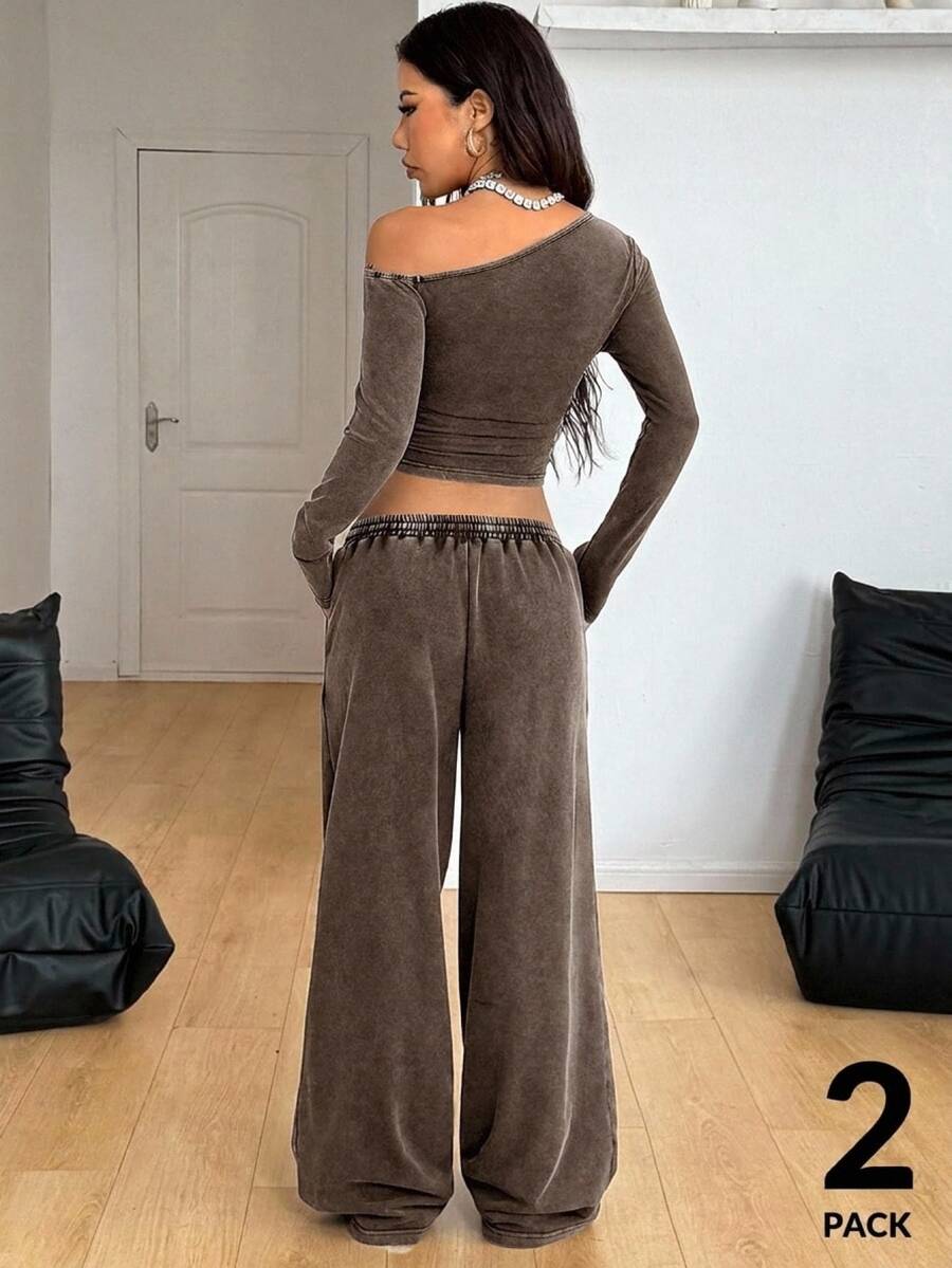 Women's two-piece knit lounge set featuring a black long sleeve asymmetrical crop top and matching high-waisted wide leg sweatpants.