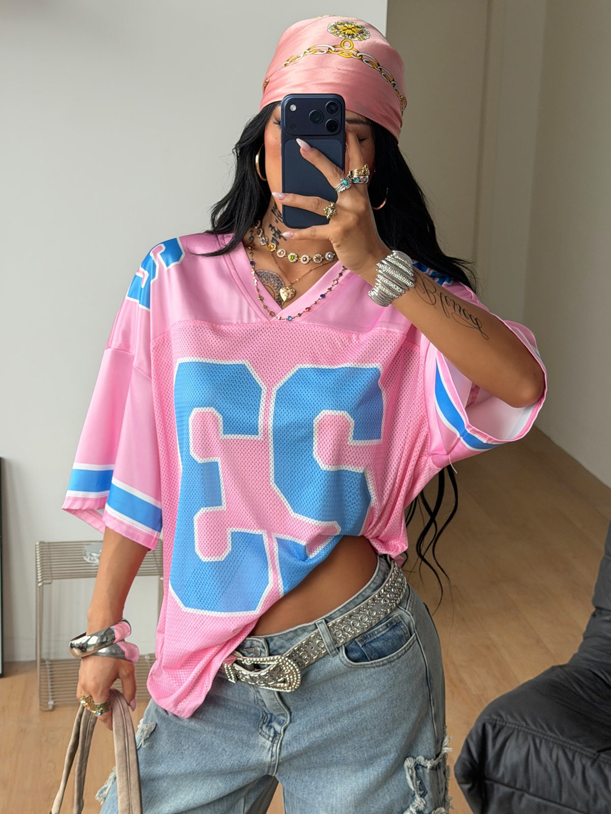 Oversized short-sleeve football jersey top featuring a V-neckline, contrast binding, and graphic number print.