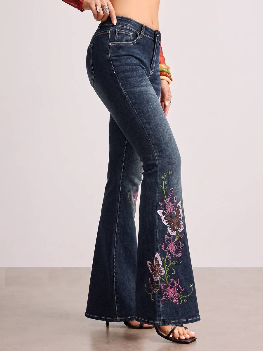 Women's blue ultra low waist flare jeans with butterfly vine embroidery and rhinestone detailing on stretch denim.