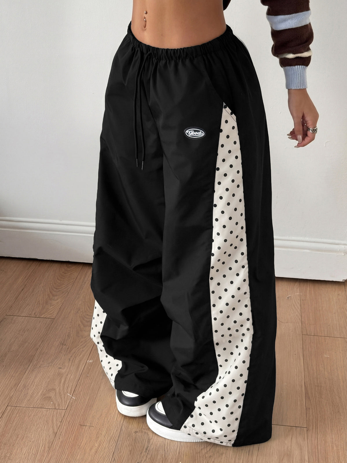 Women's black baggy jogger pants with an adjustable drawstring waist and colorblock polka dot geometric pattern.