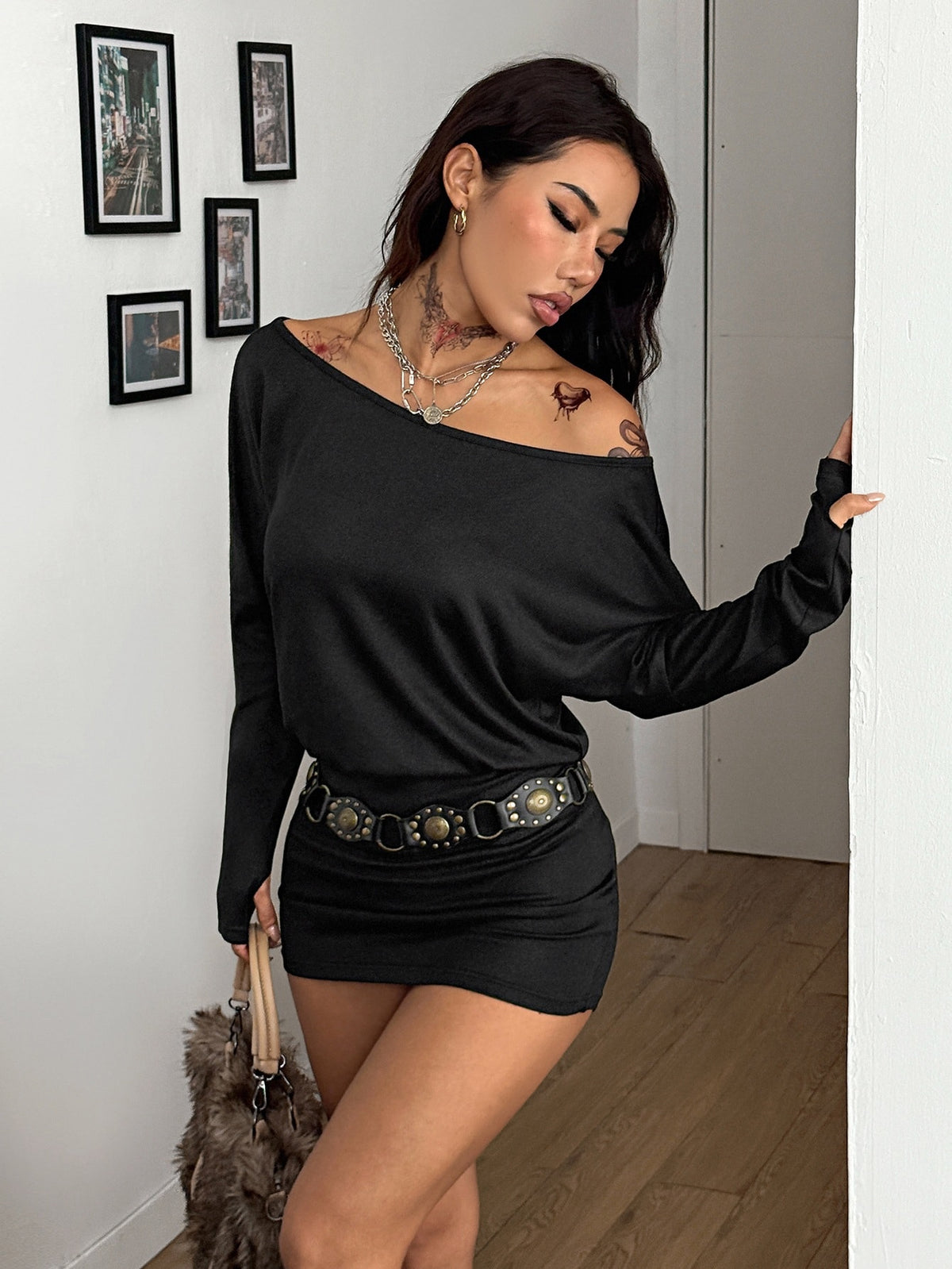 Women's long sleeve bodycon mini dress in black knitted fabric with an asymmetrical neckline and ruched accents.