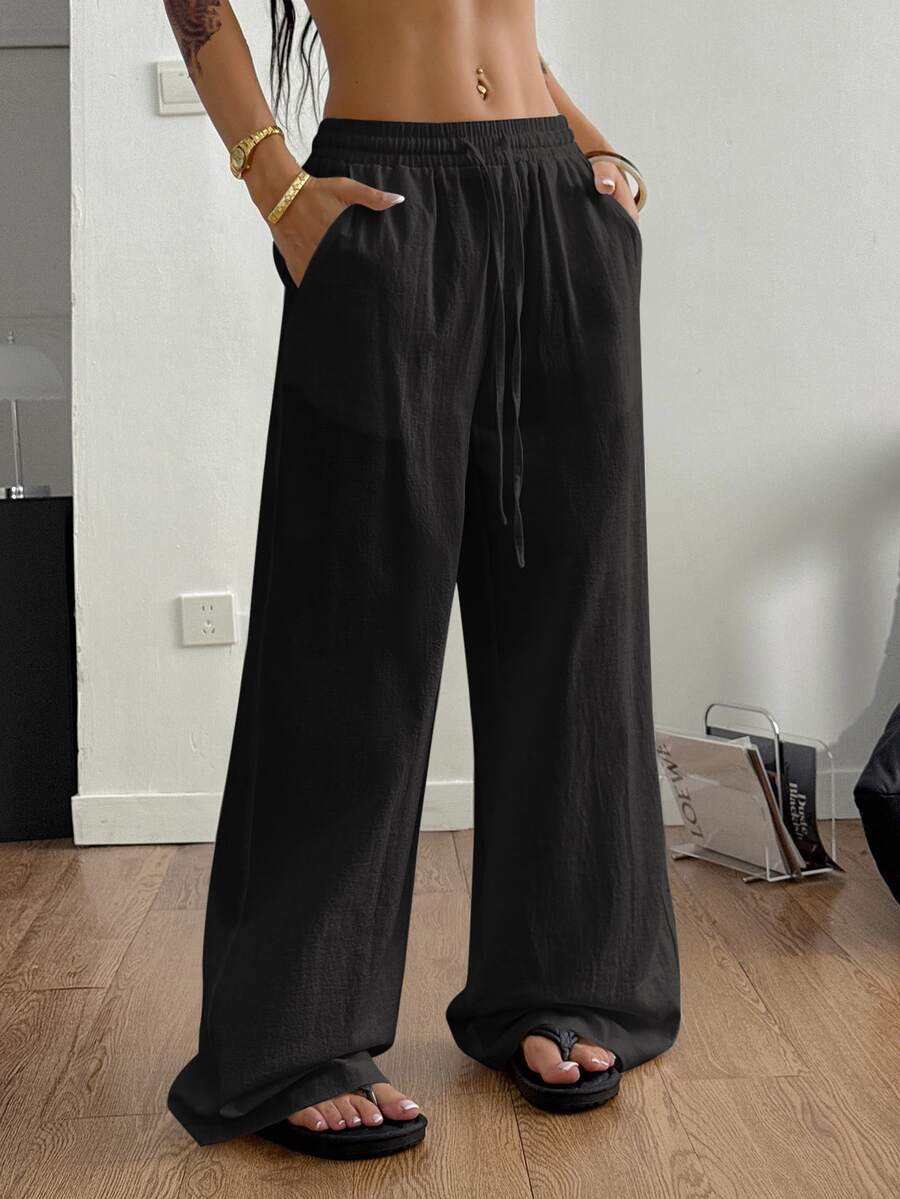 Women's loose straight leg cotton pants featuring a high waist with an adjustable drawstring knot and functional side pockets.