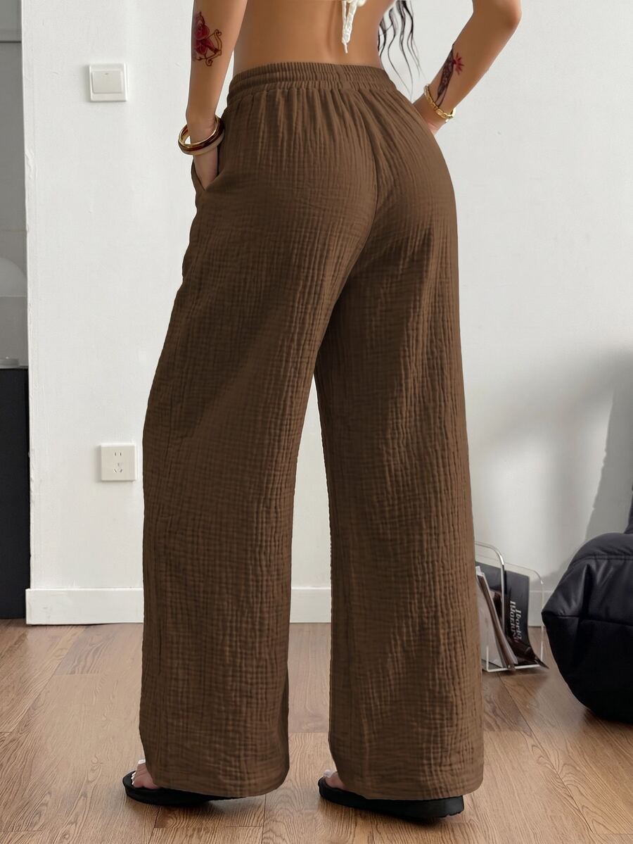 Women's black and white striped wide leg pants featuring an adjustable drawstring waist and side pockets.
