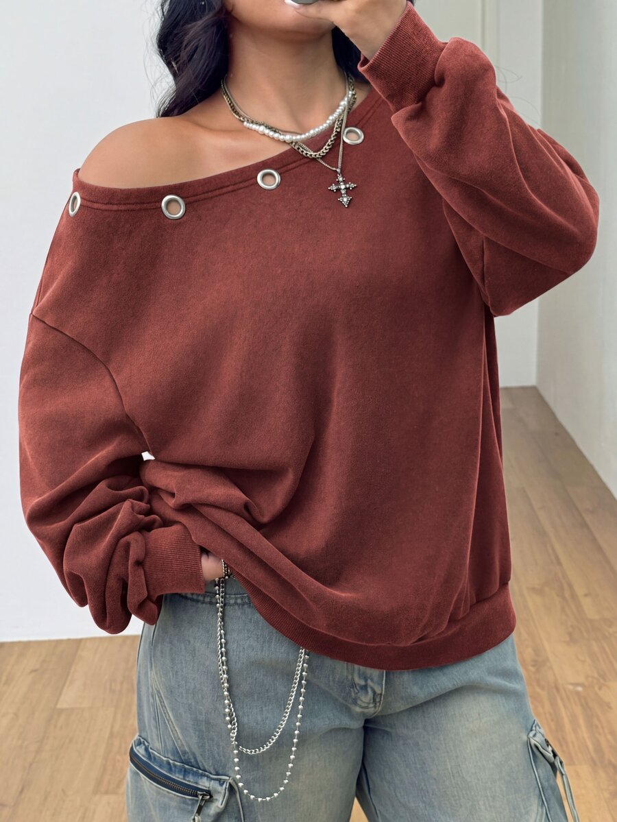 Women's oversized dark grey long sleeve sweatshirt featuring an asymmetrical boat neckline with grommet eyelet details and drop shoulders.