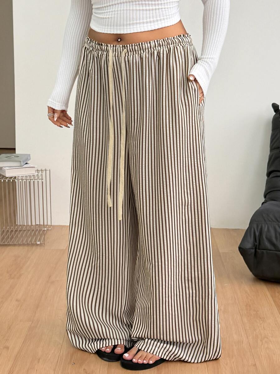Women's loose straight leg cotton pants featuring a high waist with an adjustable drawstring knot and functional side pockets.