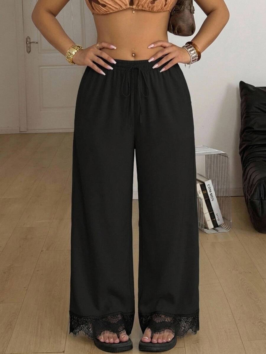 Black wide leg pants for women featuring delicate contrast lace trim at the hem, an adjustable drawstring waist, and functional pockets.