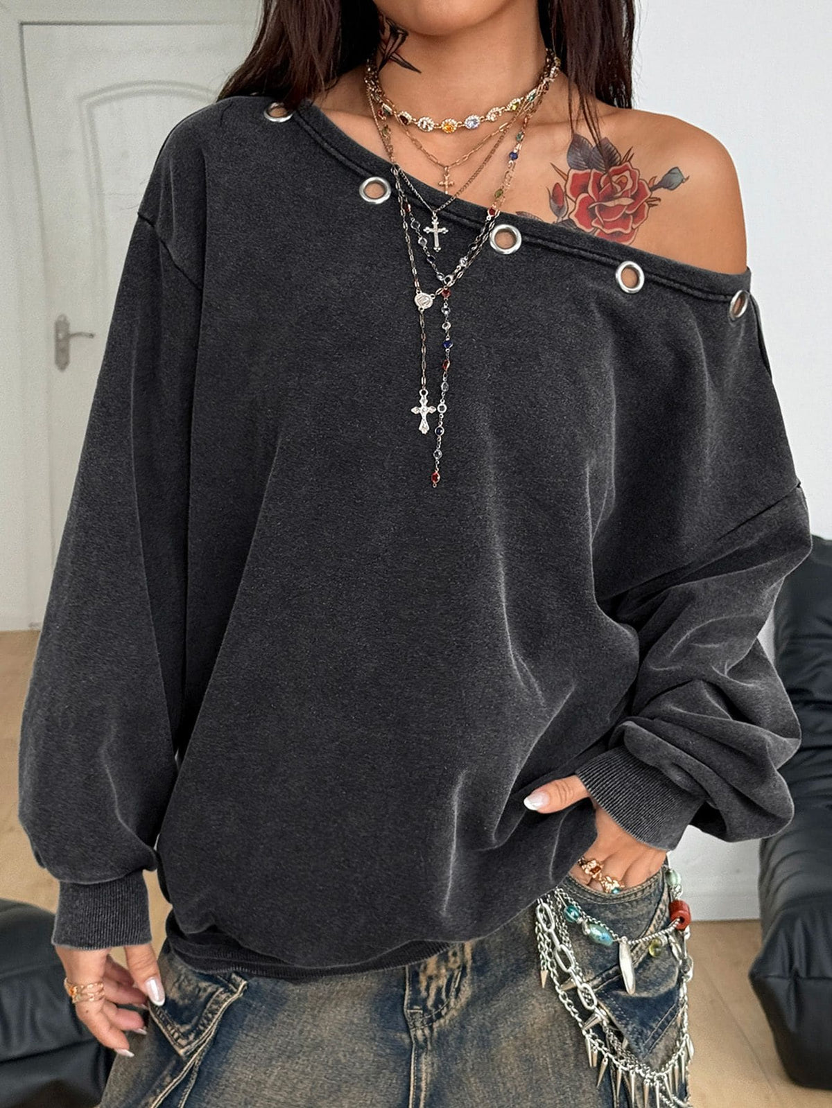 Women's oversized dark grey long sleeve sweatshirt featuring an asymmetrical boat neckline with grommet eyelet details and drop shoulders.