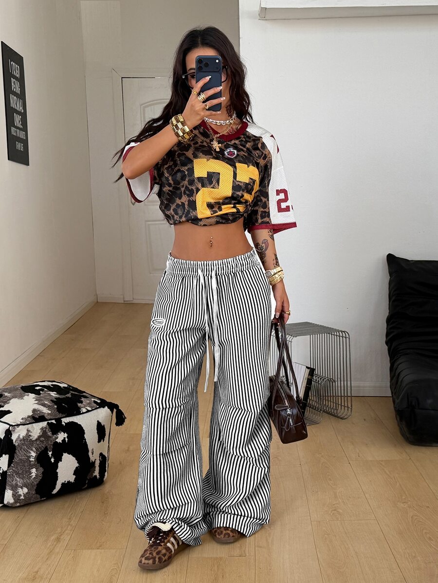 Women's black and white striped wide leg pants featuring an elastic drawstring waistband, side pockets, and a loose straight leg fit.