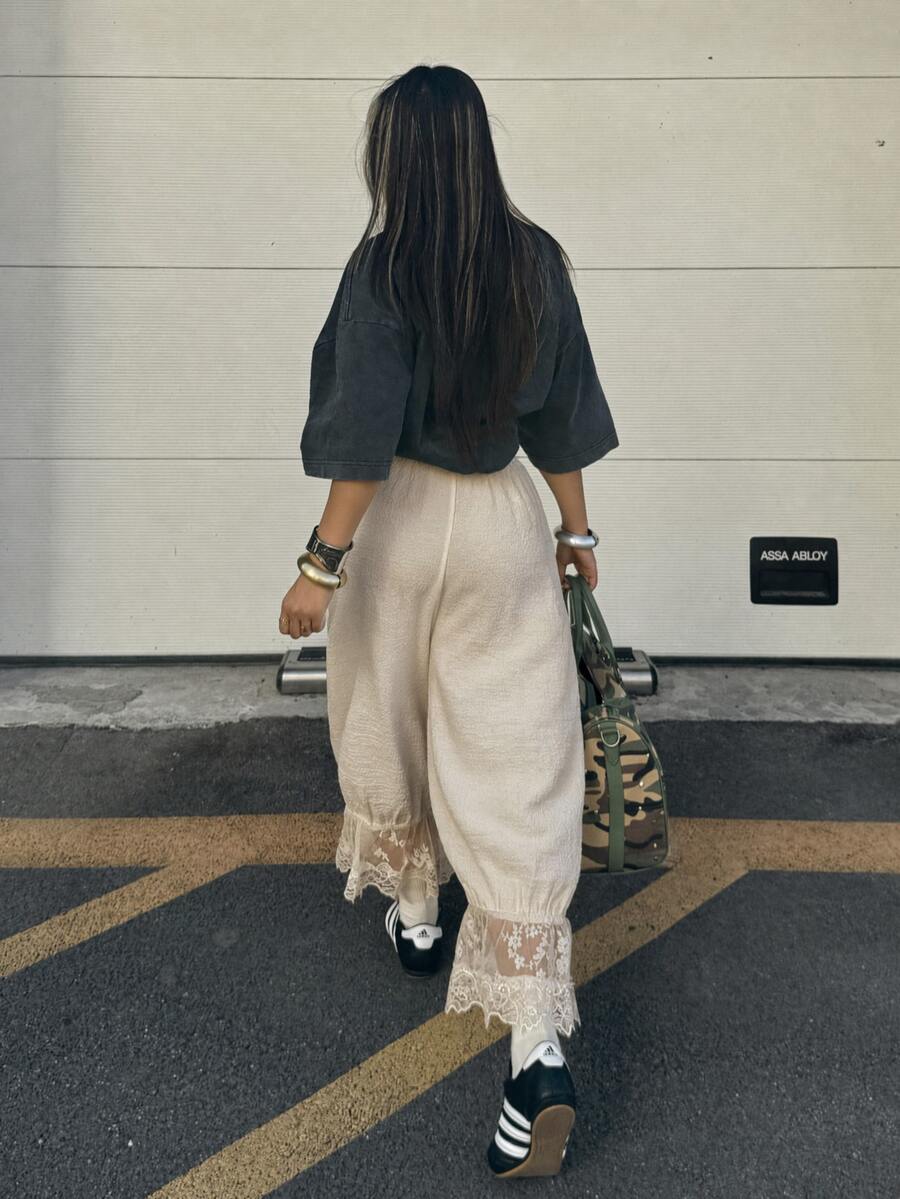 Women's loose-fitting lantern bloomer pants in capri length featuring delicate contrast lace trim and a drawstring waist.