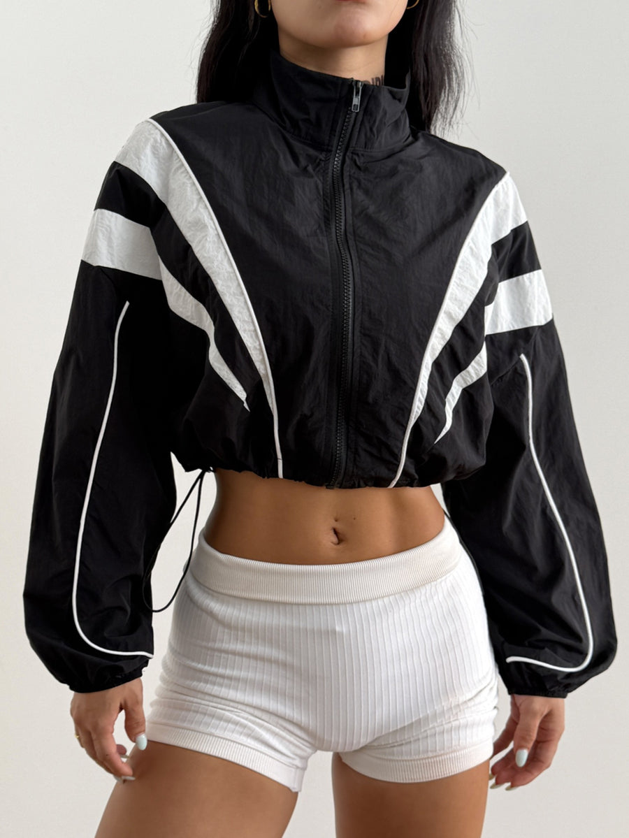 Black cropped lightweight sports jacket for women featuring colorblock stripes, a funnel neck, long sleeves, and a zipper closure.