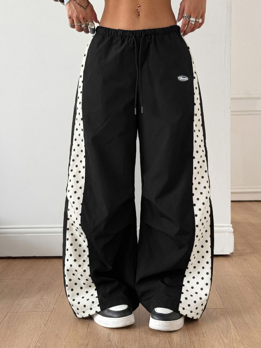 Women's black baggy jogger pants with an adjustable drawstring waist and colorblock polka dot geometric pattern.