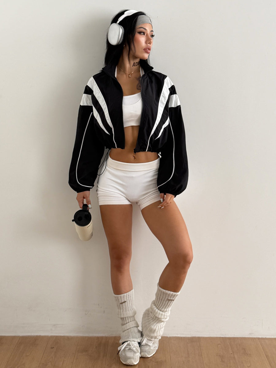 Black cropped lightweight sports jacket for women featuring colorblock stripes, a funnel neck, long sleeves, and a zipper closure.