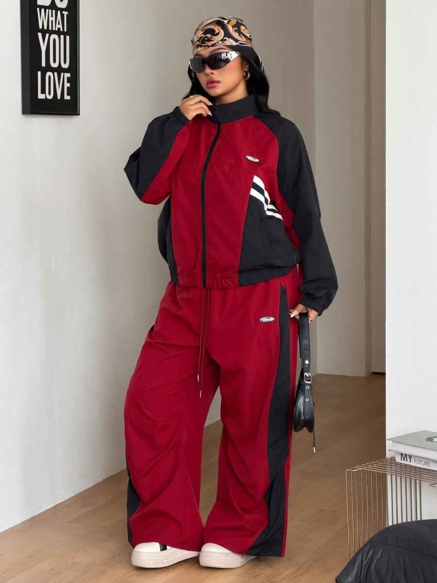 Women's plus size two-piece casual tracksuit set in black, featuring a loose-fit zip-up jacket with stand collar and matching cropped parachute pants.